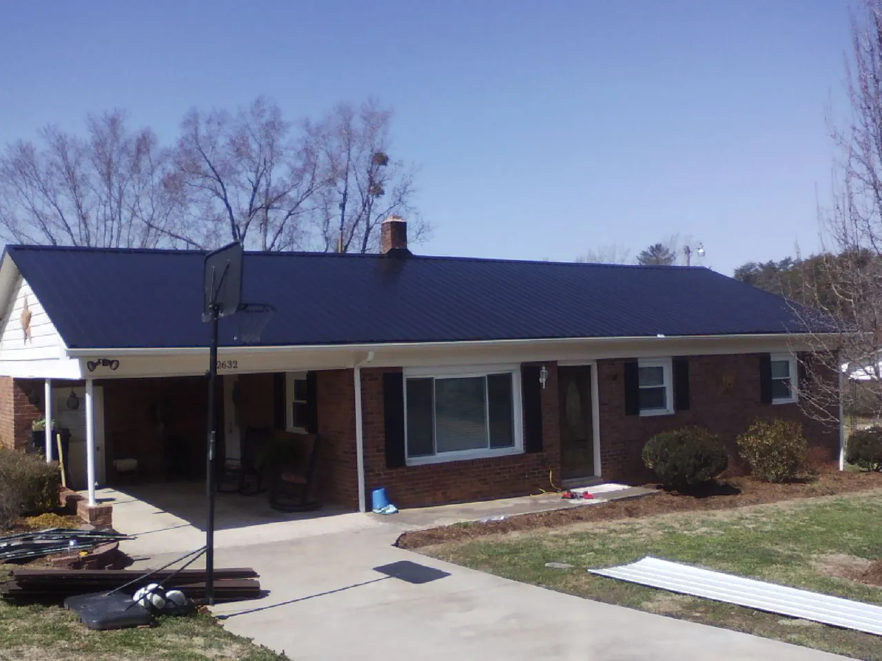 Finished dark blue metal roof on a brick ranch with a carport in Schuyler