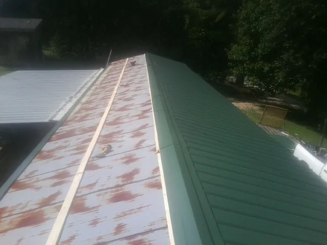 Old rusted panels beside newly installed green metal roofing — Wind Damage Roof Repair by Roofing Brothers in Schuyler
