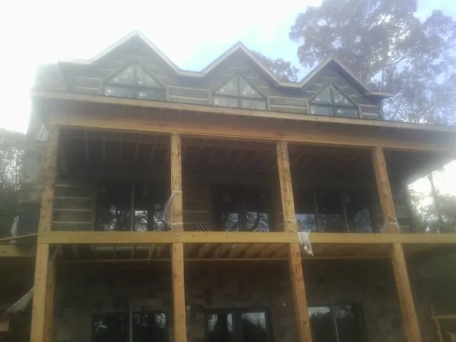 Dormers and porch framing on a large log home under construction — Roof Coating work by our crew in Schuyler