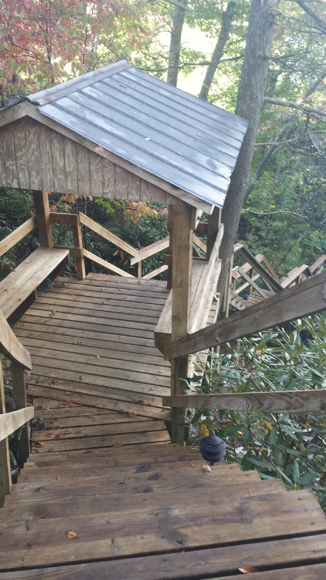 Metal roofed shelter over wooden steps on a wooded walkway — Skylight Repair & Installation work by our crew in Schuyler