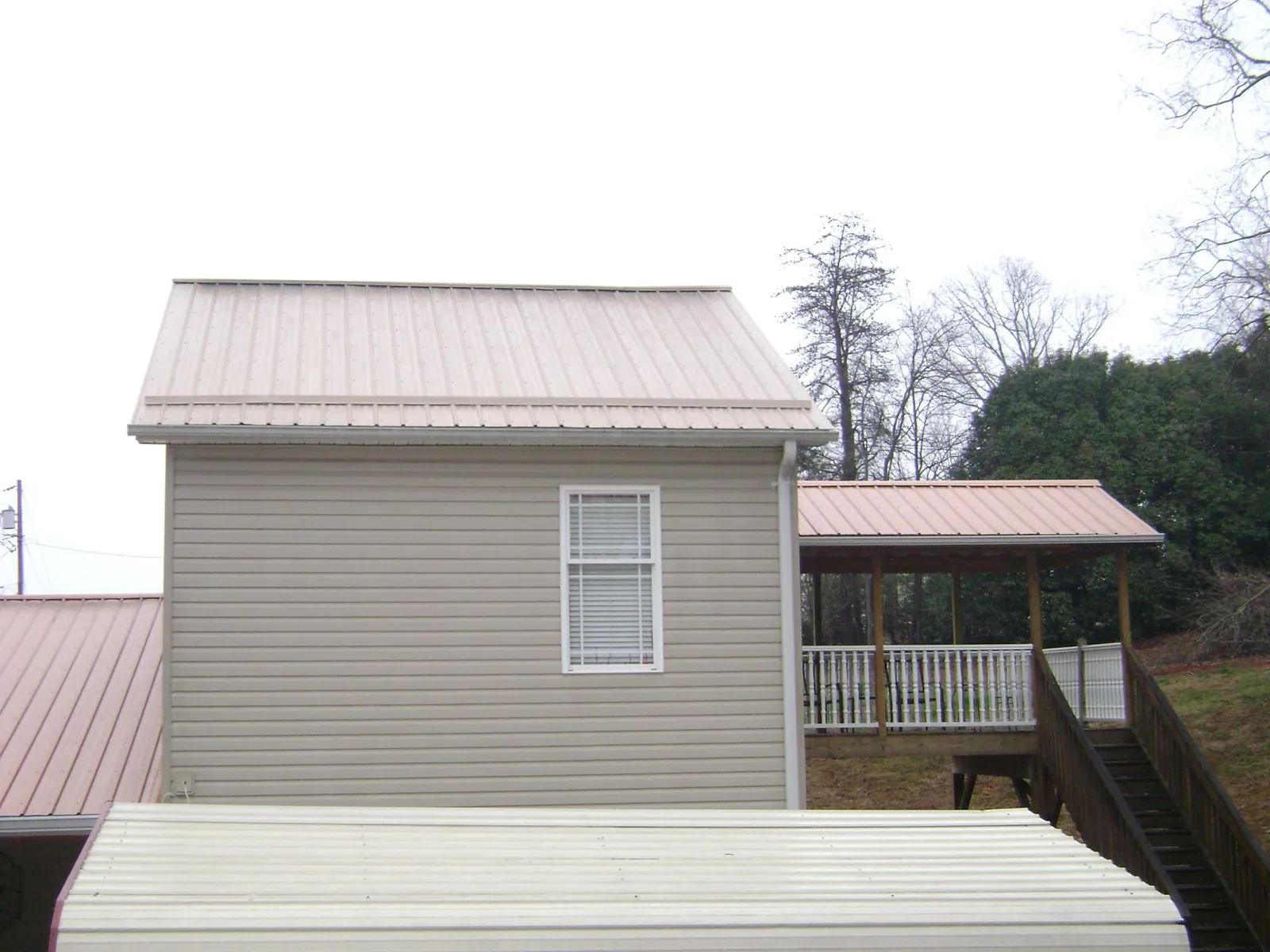 Tan metal roofs on a two story addition and attached porch, from a Roof Replacement job in Schuyler