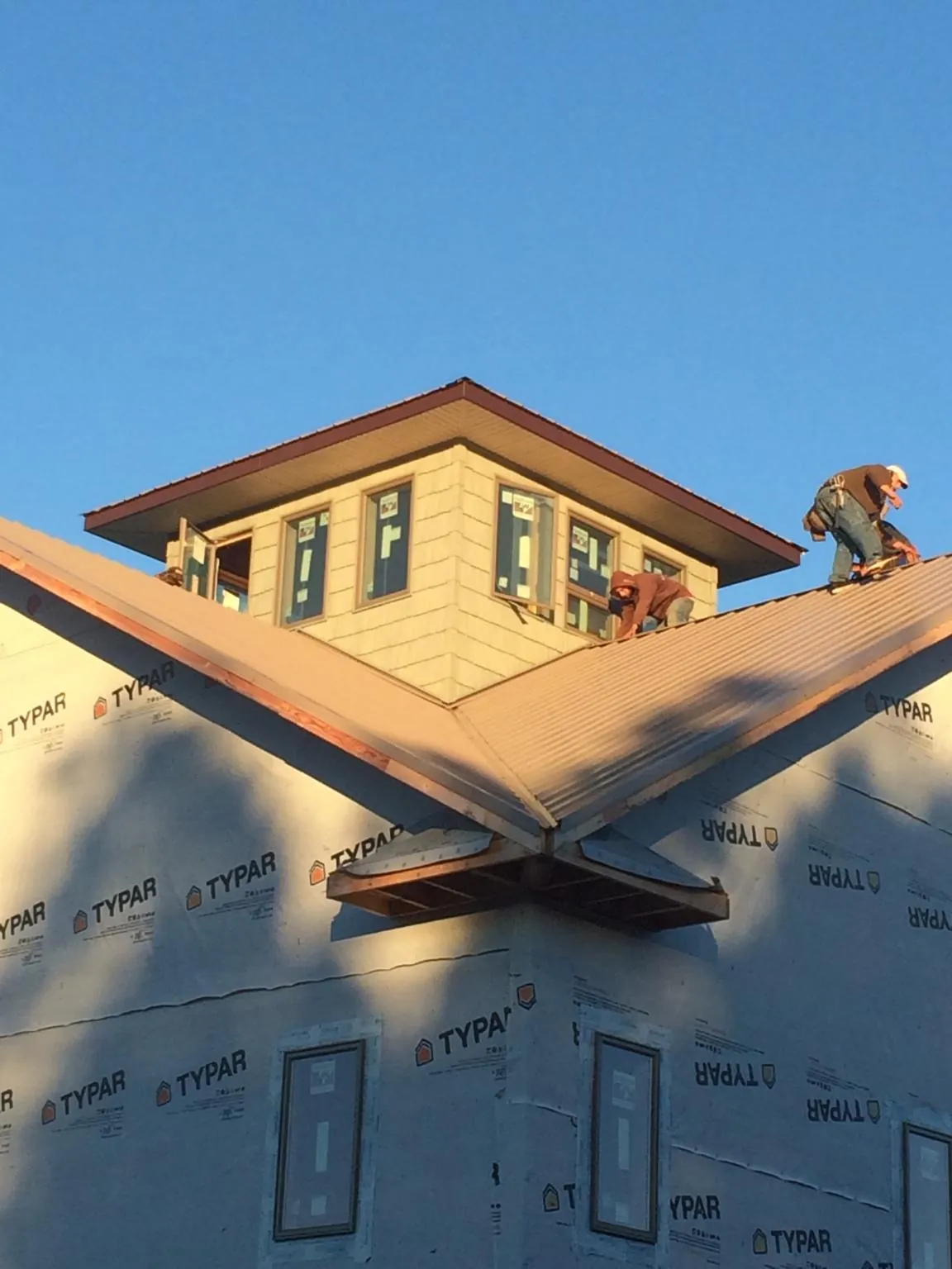 Roofers working around a rooftop cupola on a new metal roof at sunset — Roof Waterproofing in Schuyler by Roofing Brothers